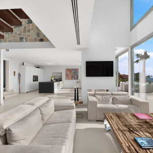 Ejemplo de salón contemporáneo, extra grande, con suelo de baldosas de porcelana, suelo beige, paredes blancas, chimenea de doble cara, marco de chimenea de yeso y televisor colgado en la pared