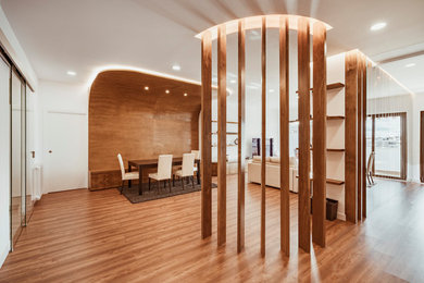 Ejemplo de salón abierto contemporáneo con paredes blancas, suelo de madera en tonos medios y televisor independiente