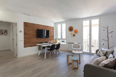 Modelo de salón abierto contemporáneo de tamaño medio con paredes blancas, suelo laminado y televisor colgado en la pared