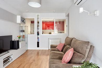 Diseño de salón cerrado nórdico de tamaño medio con paredes grises, suelo laminado, televisor independiente y suelo marrón
