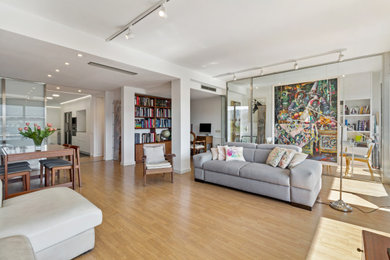 Modelo de salón abierto contemporáneo con paredes blancas, suelo de madera en tonos medios y suelo marrón