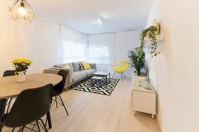 Diseño de salón para visitas abierto nórdico de tamaño medio sin chimenea con paredes blancas, suelo de madera clara y pared multimedia