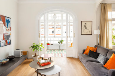 Ejemplo de salón para visitas abierto actual con paredes blancas, suelo de madera en tonos medios y suelo marrón