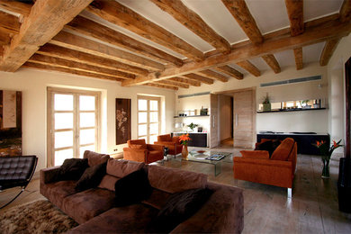 Example of a large mountain style open concept light wood floor and beige floor living room design in Madrid with beige walls and a tv stand