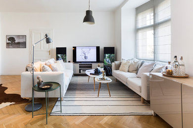 Cette image montre un grand salon nordique ouvert avec un mur blanc et un sol en bois brun.