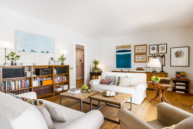 Immagine di un soggiorno mediterraneo aperto con libreria, pareti bianche, pavimento in legno massello medio e pavimento marrone