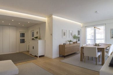 Foto de salón abierto escandinavo de tamaño medio con paredes blancas, suelo de madera clara, televisor independiente y suelo marrón