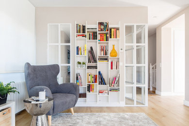 Imagen de biblioteca en casa abierta moderna de tamaño medio con paredes grises, suelo de madera clara, televisor independiente y suelo marrón