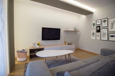 Mittelgroßes, Offenes Nordisches Wohnzimmer mit beiger Wandfarbe, braunem Holzboden und TV-Wand in Sonstige