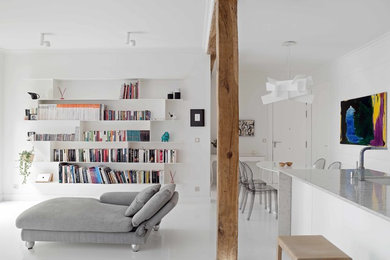 Imagen de biblioteca en casa abierta contemporánea grande con paredes blancas, suelo de cemento y televisor colgado en la pared