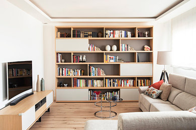 Modelo de biblioteca en casa abierta contemporánea pequeña sin chimenea con paredes blancas, suelo de madera en tonos medios, televisor independiente y suelo marrón