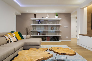 Imagen de biblioteca en casa abierta contemporánea de tamaño medio con paredes blancas, suelo de madera clara y televisor colgado en la pared