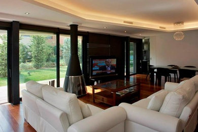 Diseño de salón para visitas abierto clásico renovado grande con paredes blancas, suelo de madera oscura, estufa de leña y televisor independiente