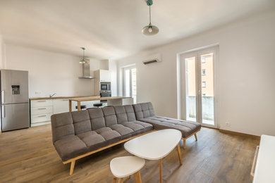 Modelo de salón abierto escandinavo de tamaño medio sin chimenea con paredes blancas, suelo de madera clara y suelo marrón
