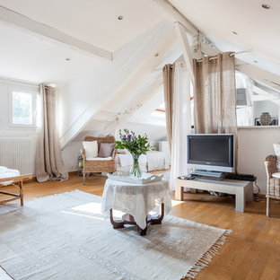 Réalisation d'un salon mansardé ou avec mezzanine ethnique avec un mur blanc, un sol en bois brun, un téléviseur indépendant et un sol marron.