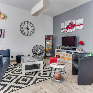 Idée de décoration pour un grand salon design ouvert avec sol en stratifié, un poêle à bois, un téléviseur indépendant, un mur gris, un manteau de cheminée en métal et un sol gris.