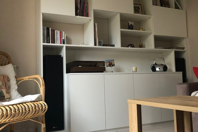 На фото: открытая гостиная комната среднего размера в современном стиле с с книжными шкафами и полками, белыми стенами, полом из керамической плитки и белым полом без телевизора с