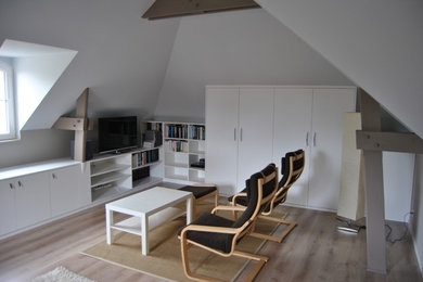 Diseño de biblioteca en casa tipo loft minimalista de tamaño medio sin chimenea con suelo de madera clara, televisor independiente y paredes blancas