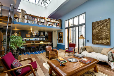 Идея дизайна: большая открытая гостиная комната:: освещение в стиле фьюжн с синими стенами, паркетным полом среднего тона и с книжными шкафами и полками без камина, телевизора