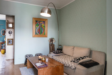Idée de décoration pour un salon design de taille moyenne et ouvert avec un mur vert et un sol en bois brun.