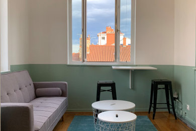 Cette image montre un petit salon design ouvert avec une bibliothèque ou un coin lecture, un mur vert, un sol en bois brun, aucune cheminée, un téléviseur dissimulé et un sol marron.