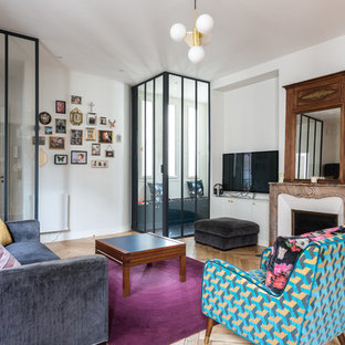 Réalisation d'un salon design de taille moyenne et ouvert avec un mur blanc, un sol en bois clair, une cheminée standard, un téléviseur encastré, un sol marron et un manteau de cheminée en pierre.