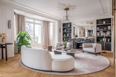 Example of a transitional light wood floor and brown floor living room design in Paris with white walls, a standard fireplace and a stone fireplace