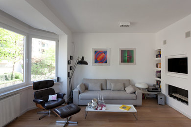 Cette photo montre un salon scandinave de taille moyenne et ouvert avec un mur blanc, parquet clair, une cheminée standard et un téléviseur encastré.