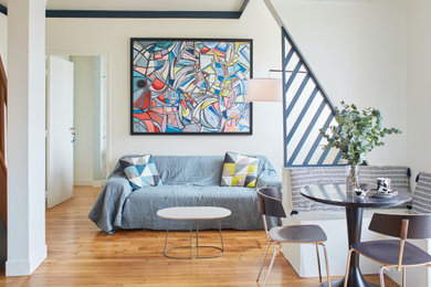 Fernseherloses Modernes Wohnzimmer ohne Kamin mit weißer Wandfarbe, braunem Holzboden und braunem Boden in Paris