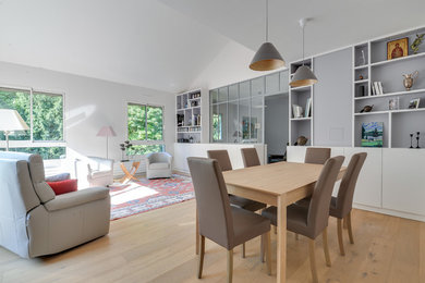 Exemple d'un grand salon mansardé ou avec mezzanine chic avec une bibliothèque ou un coin lecture, un mur blanc, parquet clair, aucune cheminée et un téléviseur dissimulé.