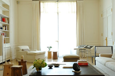 Cette photo montre un salon éclectique de taille moyenne et fermé avec un mur blanc, parquet clair, une bibliothèque ou un coin lecture et un sol beige.