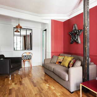Idée de décoration pour un salon bohème de taille moyenne et fermé avec un mur rouge, un sol en bois clair, une salle de réception, aucune cheminée et aucun téléviseur.
