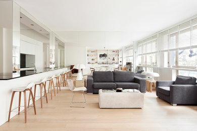 Стильный дизайн: большая открытая гостиная комната в скандинавском стиле с белыми стенами, светлым паркетным полом и с книжными шкафами и полками без камина, телевизора - последний тренд
