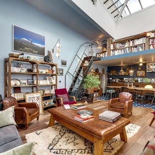 Inspiration pour un grand salon avec une bibliothèque ou un coin lecture bohème ouvert avec un mur bleu, un sol en bois brun, aucune cheminée et aucun téléviseur.