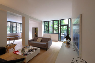 Aménagement d'un grand salon contemporain ouvert avec un mur blanc, parquet clair et un sol beige.