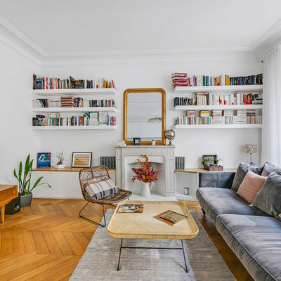 Large danish open concept medium tone wood floor and brown floor living room library photo in Paris with white walls, a standard fireplace, a stone fireplace and a tv stand