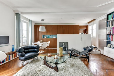 Offenes Modernes Wohnzimmer mit weißer Wandfarbe, braunem Holzboden, TV-Wand und braunem Boden in Paris
