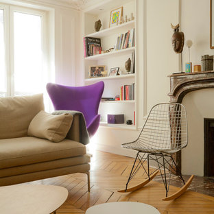 Idée de décoration pour un salon avec une bibliothèque ou un coin lecture nordique de taille moyenne et fermé avec un mur blanc, un sol en bois brun, une cheminée standard, aucun téléviseur et un manteau de cheminée en pierre.