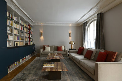 Imagen de biblioteca en casa contemporánea grande con paredes azules, suelo de madera en tonos medios y televisor retractable