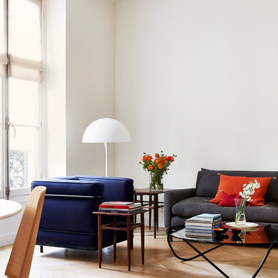 Example of a danish light wood floor living room design in Paris with white walls