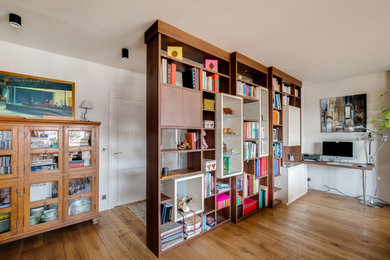 Cette photo montre un salon tendance de taille moyenne et ouvert avec une bibliothèque ou un coin lecture, aucun téléviseur, un mur blanc, parquet foncé, aucune cheminée et un sol marron.