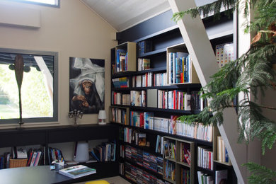 Ejemplo de biblioteca en casa abierta actual extra grande con paredes beige, suelo de cemento y suelo gris