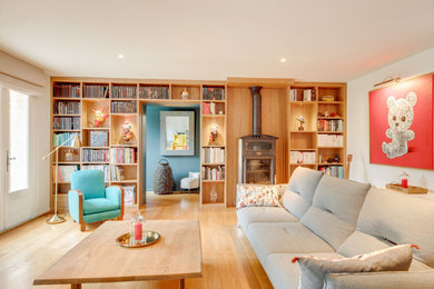 Modelo de biblioteca en casa moderna sin televisor con paredes azules, suelo de madera clara, estufa de leña y suelo marrón