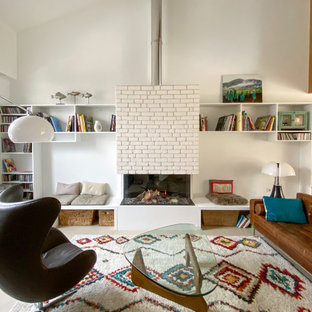 Exemple d'un salon tendance ouvert avec un mur blanc, une cheminée standard, un manteau de cheminée en brique, un sol gris et un plafond voûté.