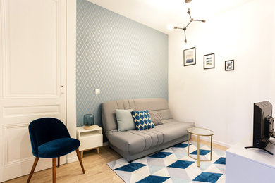 リヨンにあるお手頃価格の小さな北欧スタイルのおしゃれなLDK (青い壁、ラミネートの床、暖炉なし、据え置き型テレビ) の写真