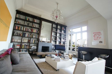 Aménagement d'un grand salon ouvert avec une bibliothèque ou un coin lecture, un mur blanc, sol en béton ciré, une cheminée standard, un manteau de cheminée en béton, un téléviseur indépendant et un sol gris.