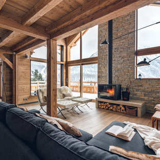Inspiration pour un salon avec une bibliothèque ou un coin lecture chalet de taille moyenne et ouvert avec un sol en bois clair, un poêle à bois, aucun téléviseur et un mur marron.