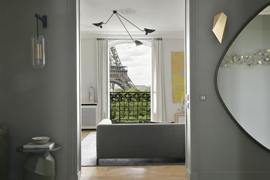 Large classic enclosed living room in Paris with white walls, light hardwood flooring, a concealed tv and brown floors.