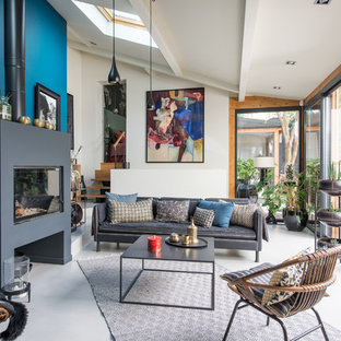 Ispirazione per un soggiorno boho chic con pareti blu, pavimento in cemento, camino classico e pavimento grigio