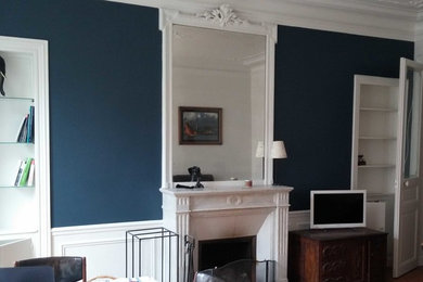 Réalisation d'un salon tradition de taille moyenne avec un sol en bois brun, une cheminée standard, un manteau de cheminée en pierre et un mur bleu.